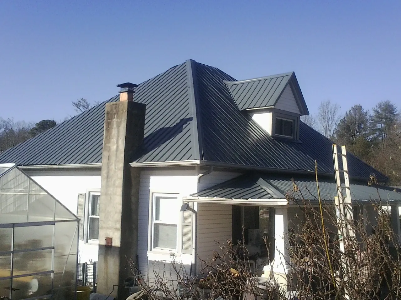 Dark blue standing seam metal roof on a white farmhouse with dormer — Slate & Tile Roof Repair by Roofing Brothers in Churchton