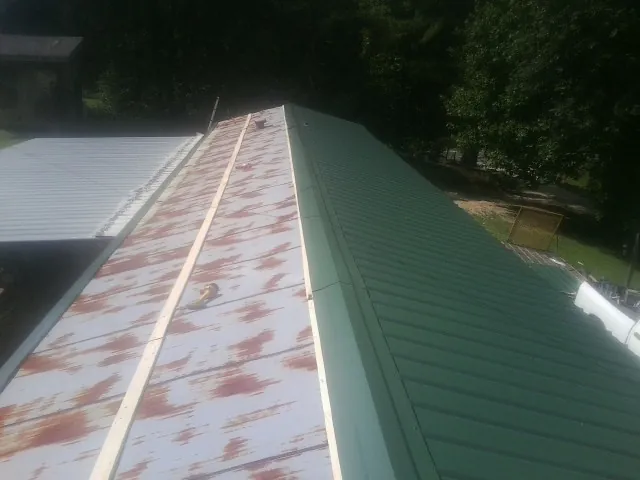 Old rusted panels beside newly installed green metal roofing — Wind Damage Roof Repair by Roofing Brothers in Churchton