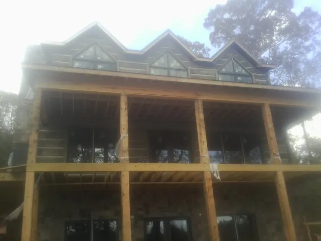 Dormers and porch framing on a large log home under construction — Roof Coating work by our crew in Churchton
