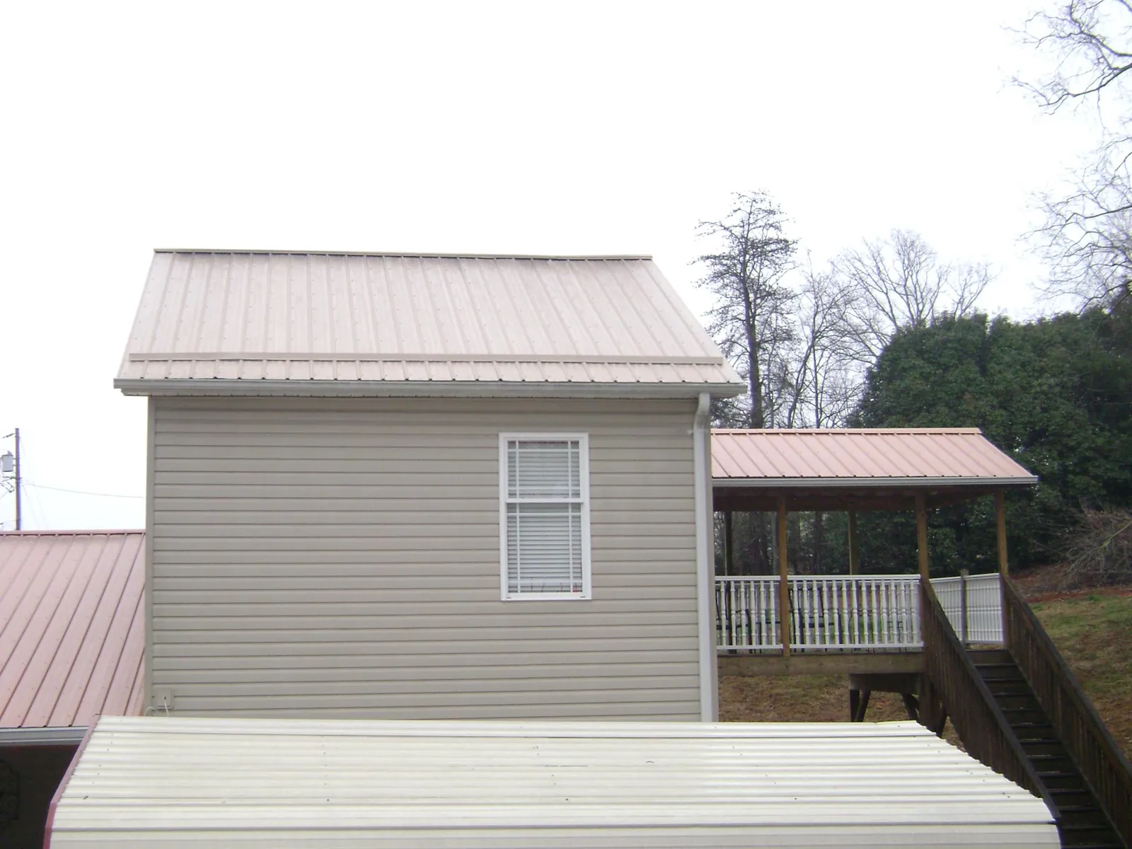 Tan metal roofs on a two story addition and attached porch, from a Roof Replacement job in Churchton