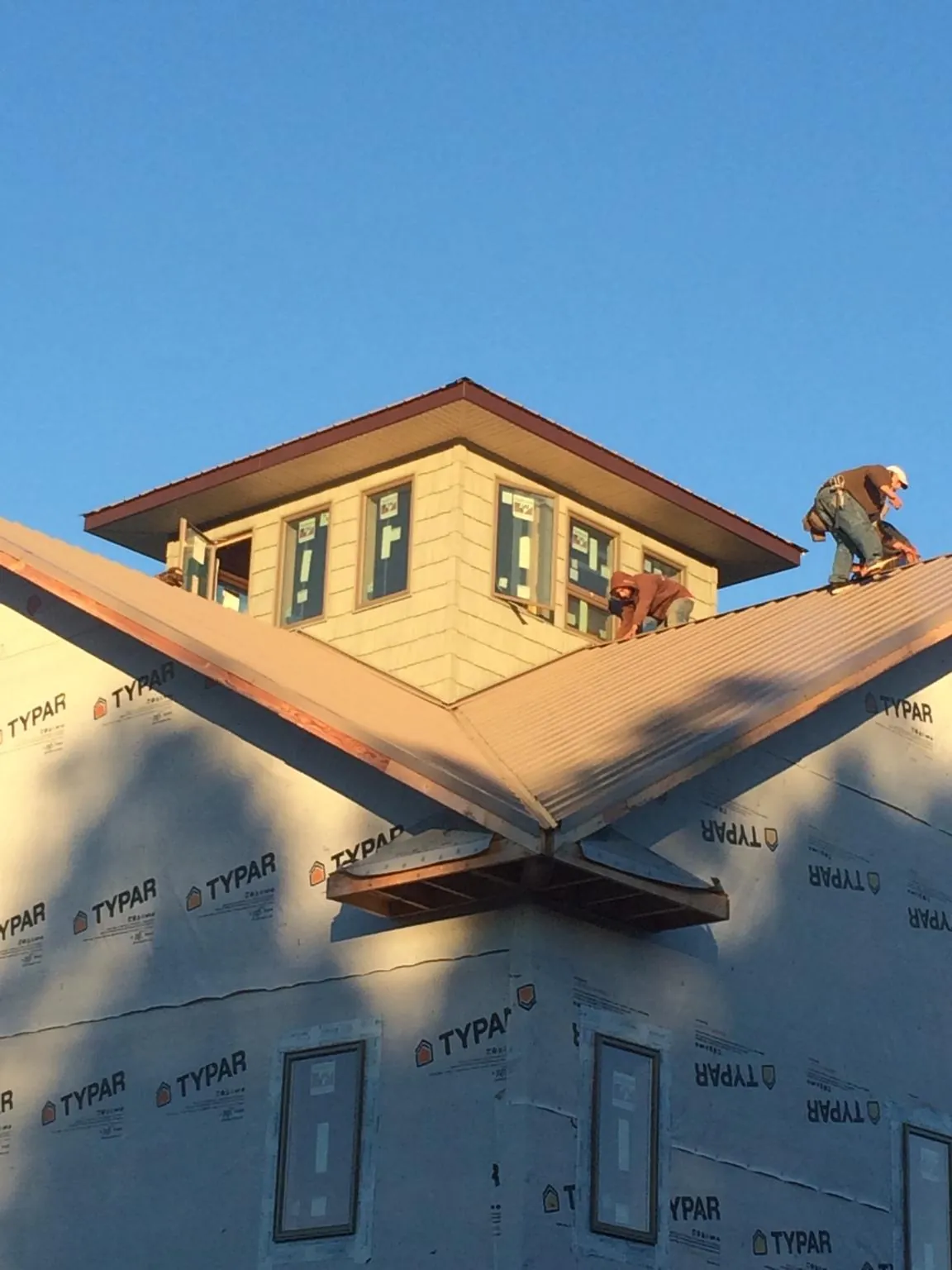 Roofers working around a rooftop cupola on a new metal roof at sunset — Roof Waterproofing in Churchton by Roofing Brothers